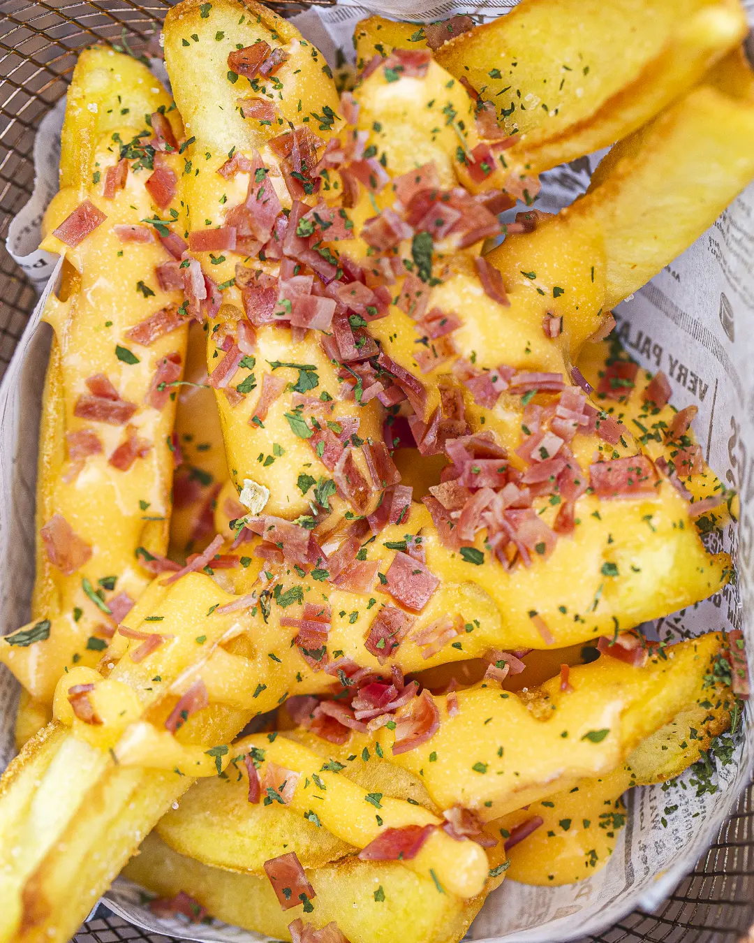 Batatas fritas com bacon sobre cesto de papel